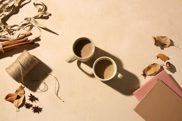 Flat lay shot of two delicious cups of coffee, decorated with dry leaves, notebook and autumn spices. Creative photo for autumn festival advertisement