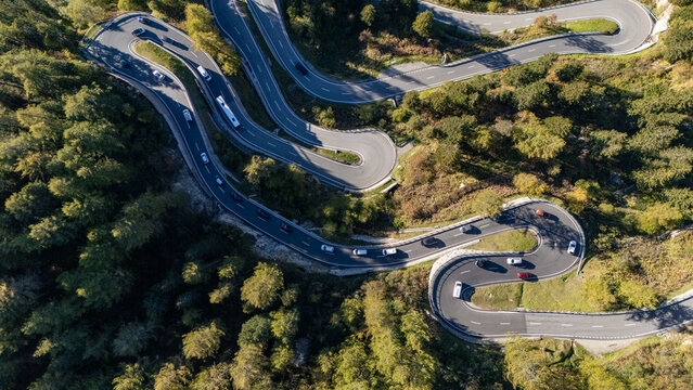 Aerial view of a winding road snaking through the lush, green mountains, a ribbon of grey against nature's vibrant tapestry, Maloja Pass, Grisons, Switzerland.