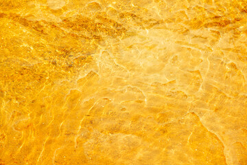 Golden water with ripples on the surface. Defocus blurred transparent white colored clear calm water surface texture with splashes and bubbles. Water waves with shining pattern texture background.