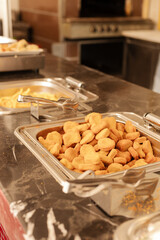 A serving station features a large tray filled with golden chicken nuggets, accompanied by other dishes. The setting is cozy, perfect for casual dining gatherings