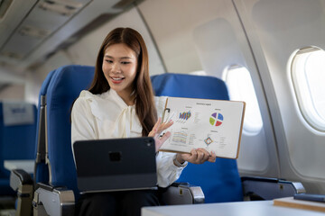 Asian businesswoman having video call presenting report in airplane
