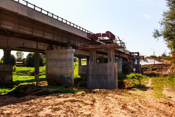 Concrete bridge expansion project underway, with new supports and steel frames. Construction site...