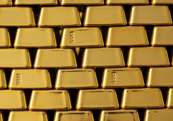 Fototapeta premium Stacked gold bars with shiny metallic surfaces arranged in rows, symbolizing wealth, prosperity, and financial investment