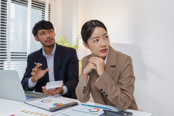 A group of business professionals engaged in a serious office discussion, analyzing financial reports and exchanging ideas to solve problems and make effective corporate decisions.