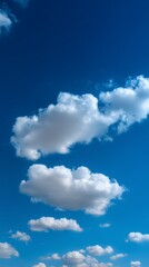 Vertical view of bright blue sky with soft white clouds. Ideal natural background for banners, mobile designs, posters, or web content with clean copy space and uplifting visual mood.