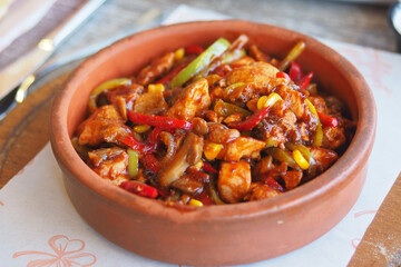 Spicy chicken stir-fry served in a clay bowl