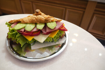 Delicious croissant sandwich with fresh vegetables and meats