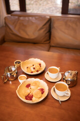 Relaxing tea time in a cozy lounge area after sauna session, with cups of tea, teapots and desserts on a wooden table near window in warm interior.