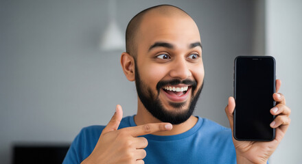 A man in a blue t-shirt points at a blank smartphone screen, emphasizing modern digital connectivity and technology usage.