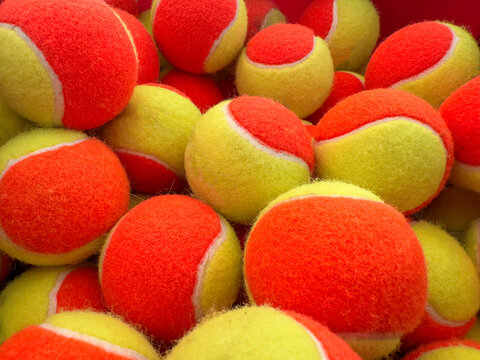 Close-up view of many red and yellow tennis balls forming a colorful pattern. Vibrant texture background