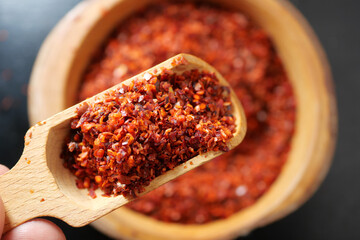 Chili flakes in wooden scoop and bowl ready for cooking