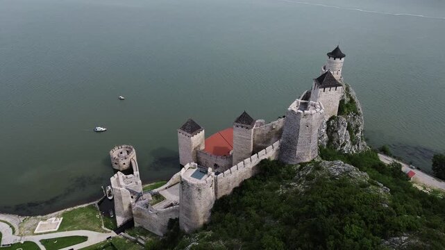 4k footage showing the medieval Golubac Fortress on the Danube River in Serbia. Aerial view of historic towers surrounded by green hills in spring.
