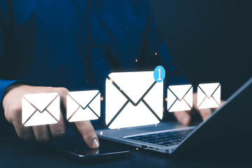 Businessman using smartphone and laptop with floating email icons, representing digital communication, online messaging, email marketing, cloud data, and modern technology connection.