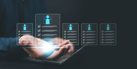 Businessman holding digital checklist with human icons on virtual screen, symbolizing HR technology, recruitment management, employee analytics, and modern workforce innovation concept hologram,