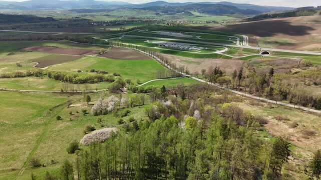 Aerial view of a highway tunnel entrance in green countryside with fields and hills in spring