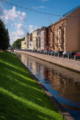 Urban Canal with Historic Buildings and Reflections on Water Surface under Blue Sky