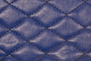 Obraz premium A detailed close-up of a luxurious deep blue, textured faux leather surface with a distinct diamond-shaped quilted stitching pattern, ideal for a background.