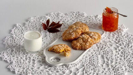 Homemade pumpkin oatmeal cookies with a sugar crust and milk, served on a white crochet napkin.