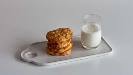 A minimalist photo of sugar-crusted cookies on a plate with a glass of milk.