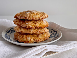 Close-up at eye level of homemade sugar-crusted cookies served on a blue patterned plate with folded linen napkins underneath.