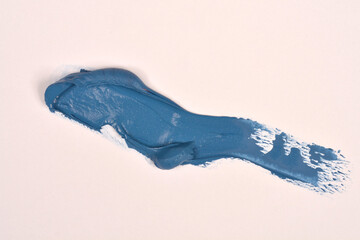 A thick, textured stroke of matte dark blue paint is smeared diagonally across a clean white background