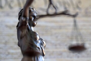 Lady Justice bronze statue and US Constitution blurred page close up. Lawsuit and punishment in United States of America