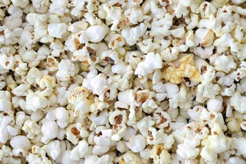 Big amount of salted popcorn in warm yellow tones close up