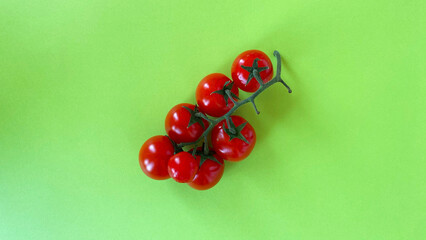 Fresh red cherry tomatoes arranged on a vibrant green background, showcasing their glossy texture and natural appeal for culinary presentations