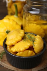 Pickled pattypan squashes with dill on wooden table, closeup