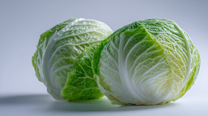 Fototapeta premium Close up of two green and white cabbages on a white surface studio shot