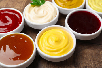 Different tasty sauces in bowls on wooden table, closeup