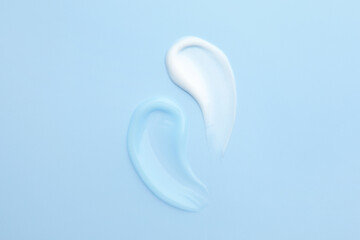 Samples of different cosmetic products on light blue background, flat lay