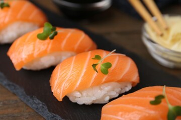 Delicious nigiri sushi with salmon and microgreens on wooden table, closeup