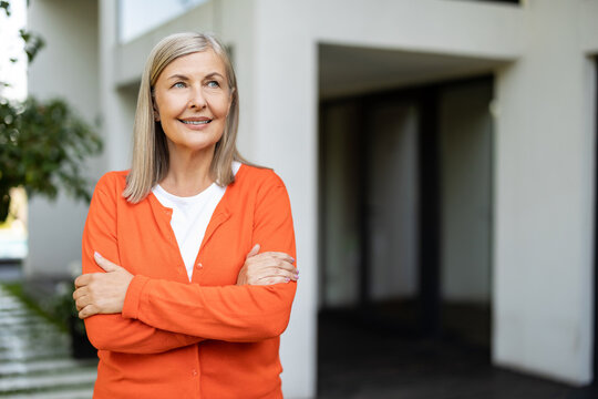 Pretty mature blonde woman in orange shirt looking contented
