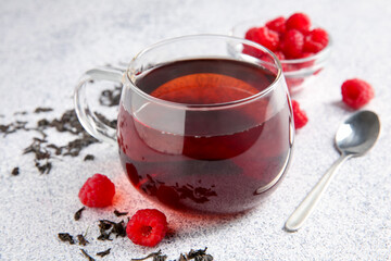 Delicious tea, raspberries and brew served on light table, closeup