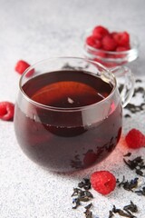 Delicious tea, raspberries and brew served on light table, closeup