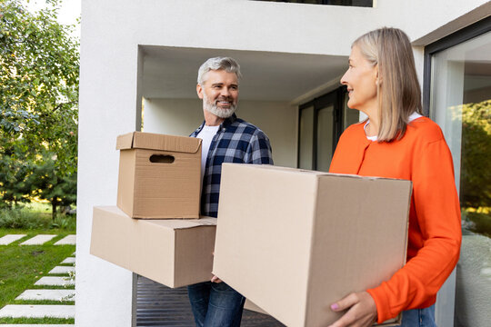 Senior couple enjoying moving day carrying boxes