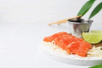 Fresh salmon sashimi with sliced radish, lime and soy sauce on light tiled table, closeup. Space for text
