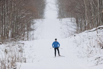 Cross-country skier ascending snowy forest trail