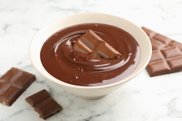 Melted chocolate and pieces on white marble table, closeup
