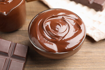 Melted chocolate and piece on wooden table, closeup