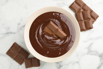 Melted chocolate and pieces on white marble table, flat lay