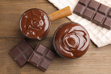 Melted chocolate and pieces on wooden table, flat lay