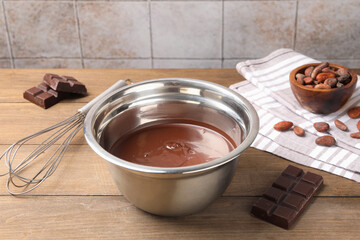 Melted chocolate, beans and pieces on wooden table