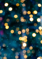 Golden bokeh lights on a dark background. Snowflakes falling down. Christmas magical light background, overlay or lens flare effect