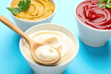 Different sauces on light blue background, closeup
