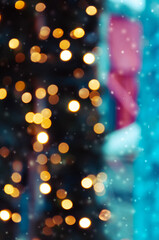 Golden bokeh lights on a dark background. Snowflakes falling down. Christmas magical light background, overlay or lens flare effect