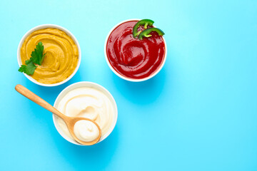 Different sauces on light blue background, flat lay. Space for text