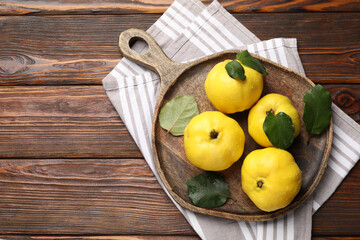 Fresh ripe quinces with leaves on wooden table, top view. Space for text