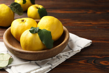 Fresh ripe quinces with leaves on wooden table, closeup. Space for text